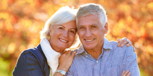 older couple smiling with a fall background